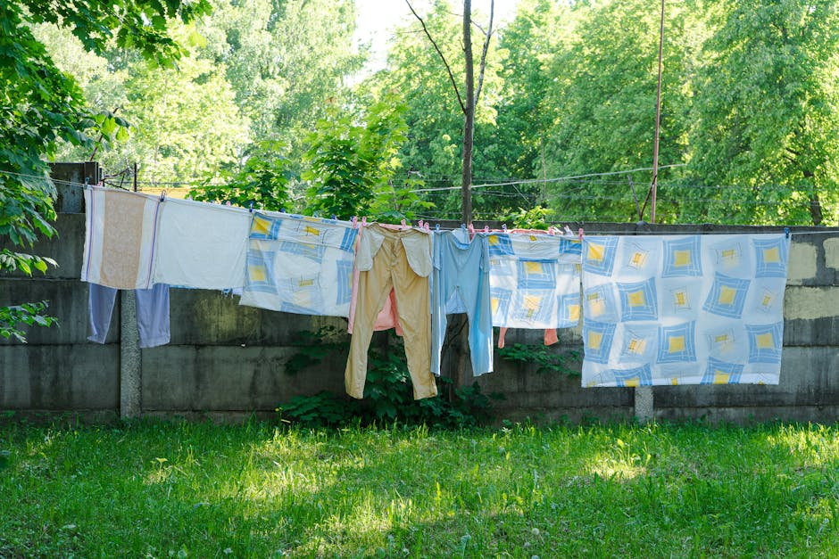 Vibrant clothes and sheets drying on a line outside surrounded by lush greenery.