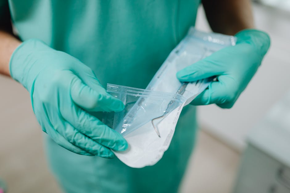 Close-up of gloved hands opening a sterile dental tool packet in a clinical setting.