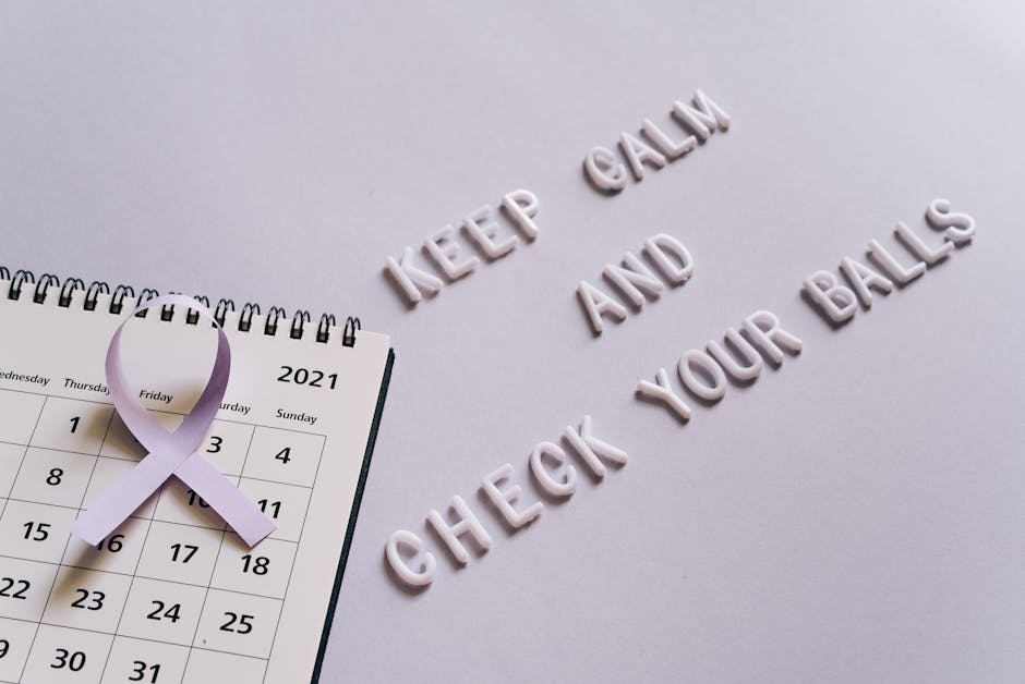 Flat lay image of a calendar with a purple ribbon and the text 'Keep Calm and Check Your Balls' for testicular cancer awareness.